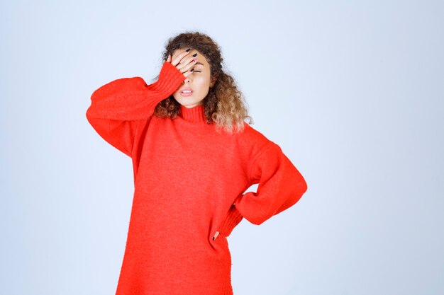 mujer en sudadera roja se ve cansada y con sueño.