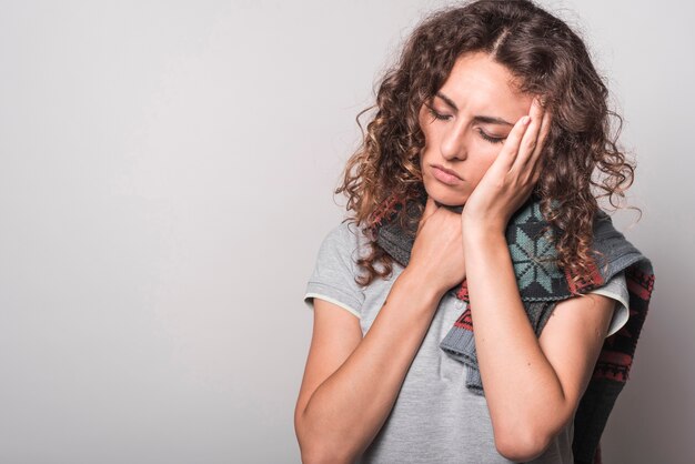 Mujer con sueño teniendo frío y tos sobre fondo gris