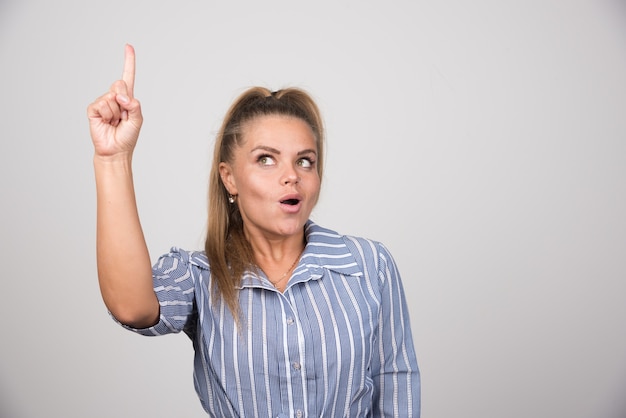 Mujer de suéter azul apuntando a algo.