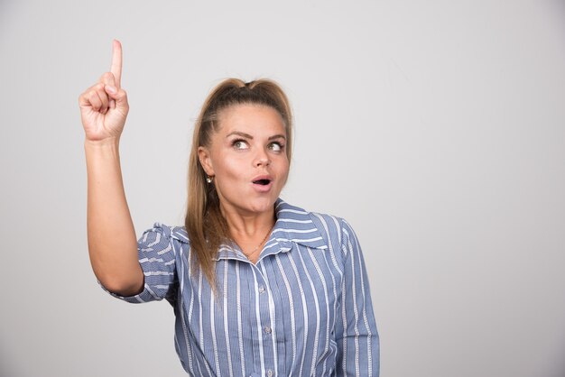 Mujer de suéter azul apuntando a algo.