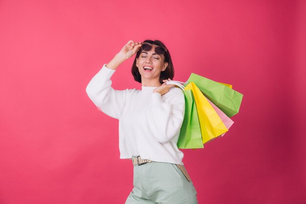 Mujer en suéter blanco casual y gafas de sol en la pared roja