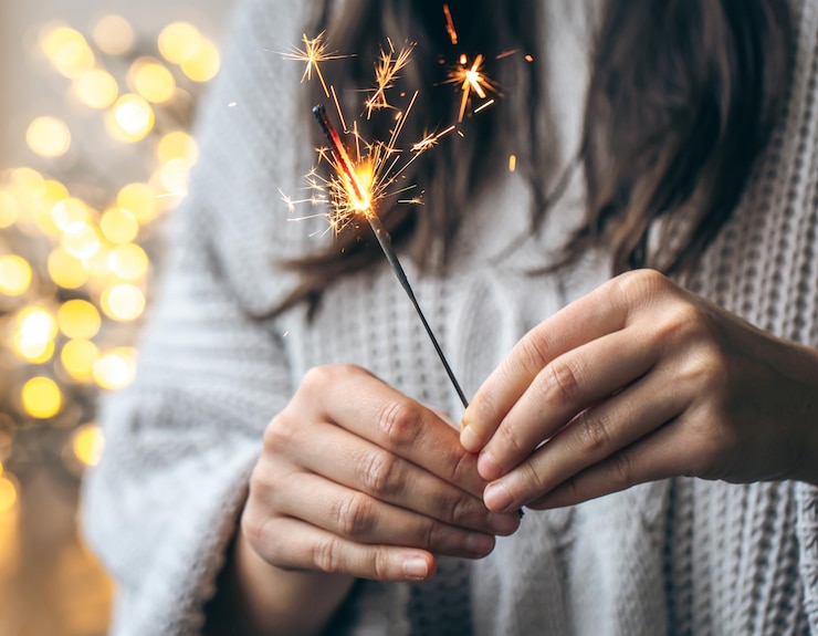 Foto gratuito mujer con suéter gris sosteniendo chispas ardientes de cerca