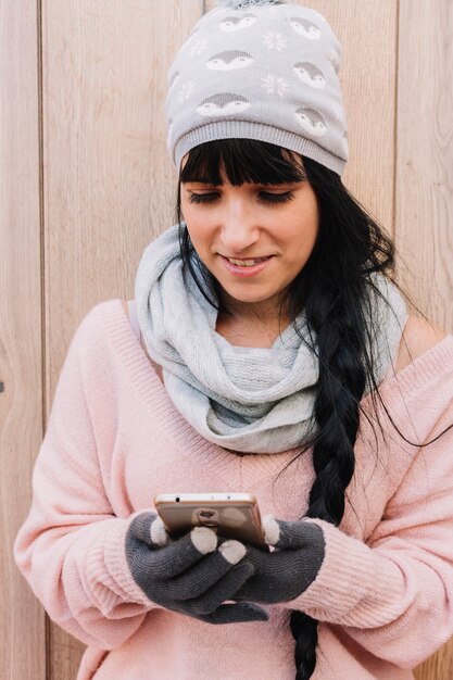 Mujer en suéter mirando smartphone