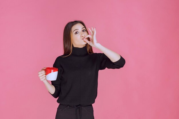 Mujer de suéter negro tomando café y disfrutando del sabor.
