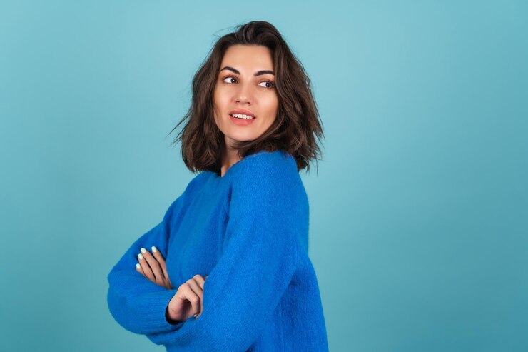 Foto gratuito mujer con un suéter de punto azul y maquillaje natural, cabello corto y rizado, con una sonrisa radiante infecciosa de muy buen humor