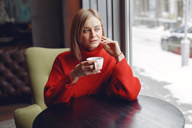 Mujer con un suéter rojo. Señora bebe un café.