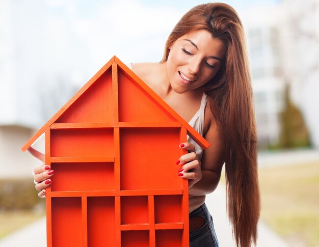 Mujer sujetando una casa de color naranja