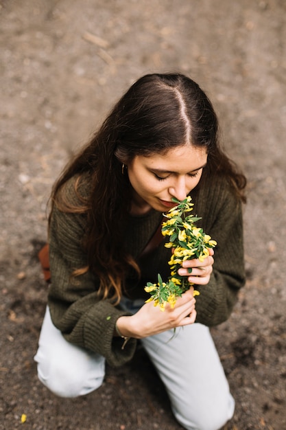 Foto gratuita mujer sujetando unas flores silvestres en la naturaleza