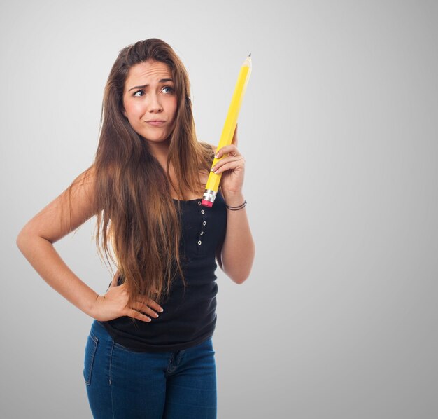 Mujer sujetando un lápiz gigante