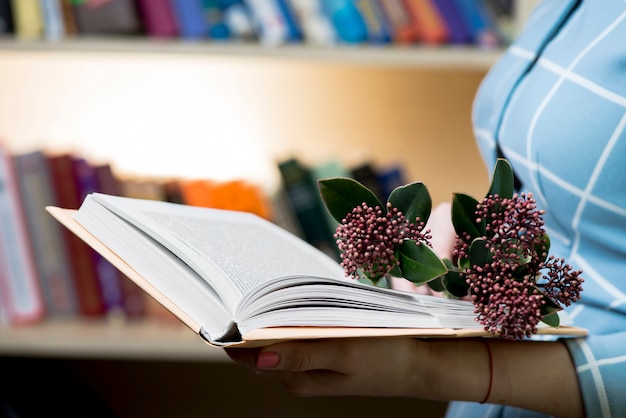 Mujer sujetando un libro con flores