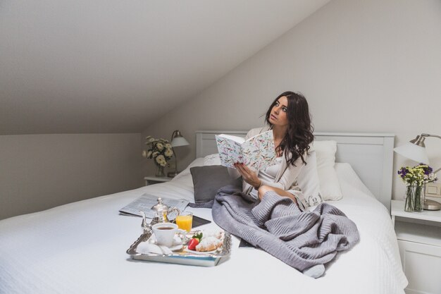 Mujer sujetando un libro y mirando hacia arriba