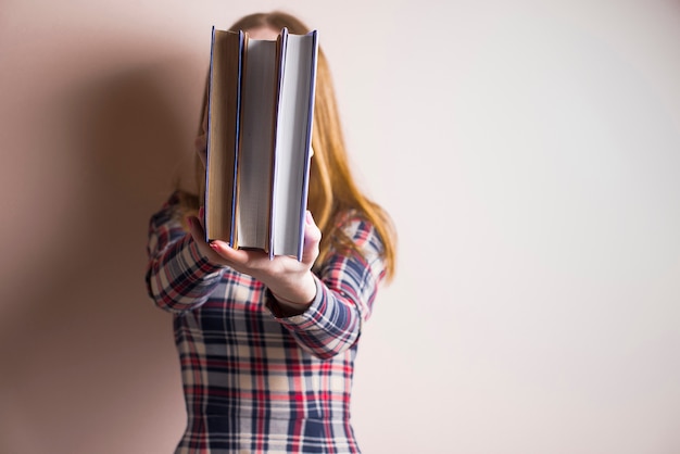 Mujer sujetando tres libros delante de su cara