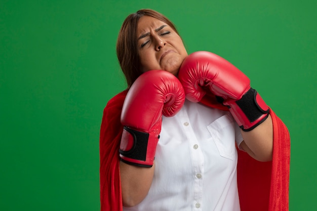 Mujer superhéroe de mediana edad con guantes de boxeo - aislado sobre fondo verde