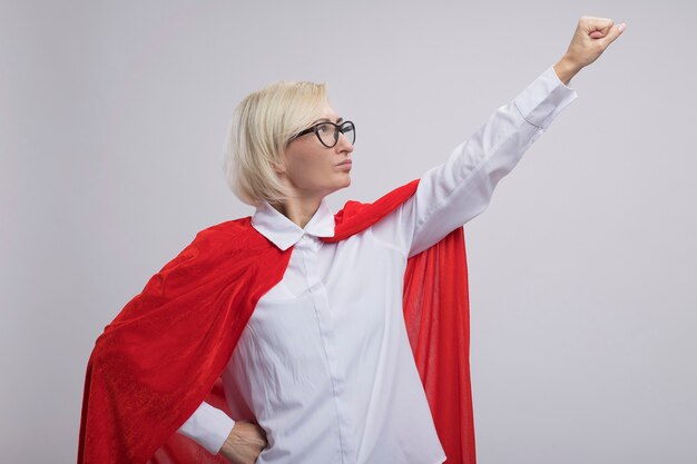 Mujer de superhéroe rubia de mediana edad confiada en capa roja con gafas mirando hacia arriba haciendo gesto de superman