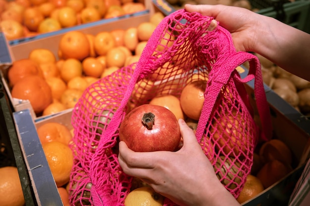 Foto gratuita una mujer en un supermercado pone fruta en una bolsa de compras.