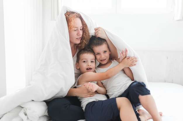 Mujer y sus hijos envueltos en manta.