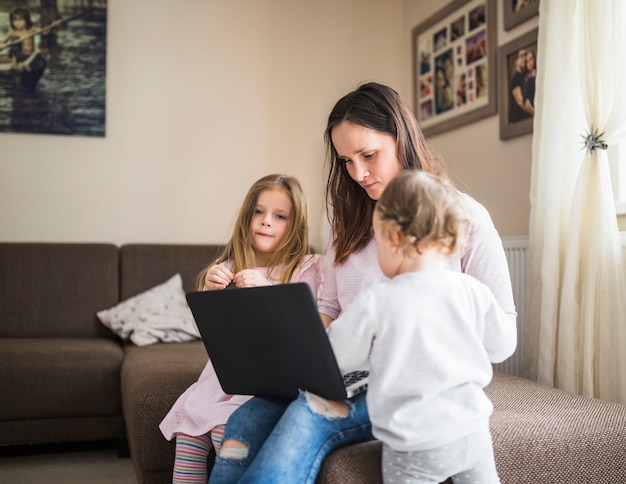 Mujer con sus hijos usando laptop