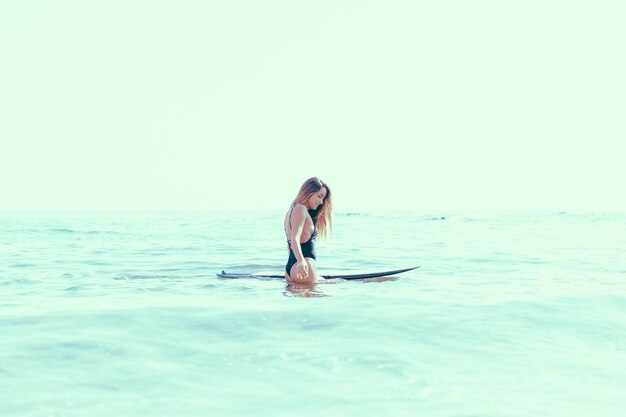 Mujer con tabla de surf en agua