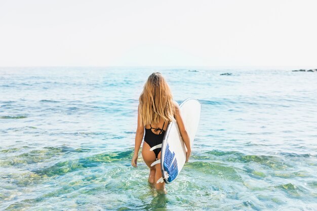 Mujer con tabla de surf en la playa