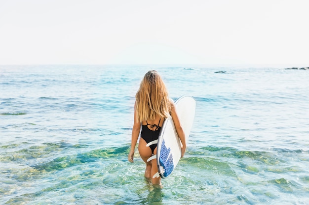 Mujer con tabla de surf en la playa