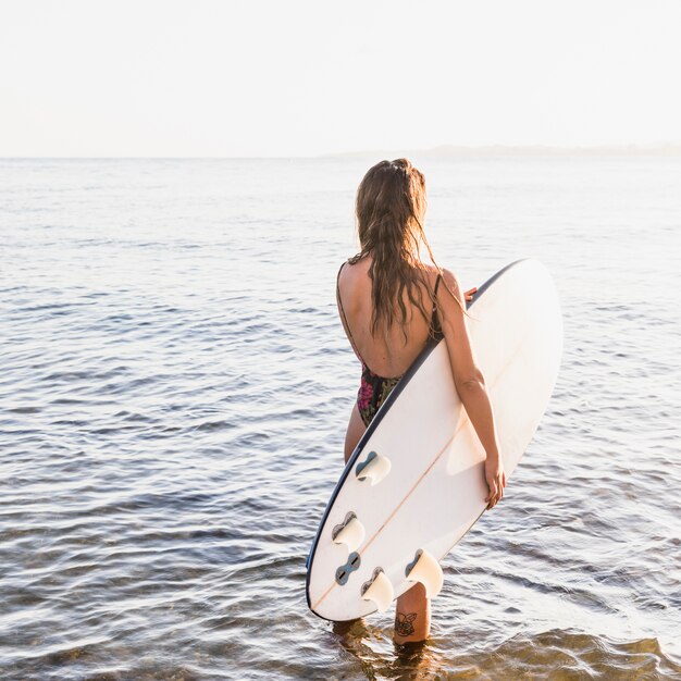 Mujer con tabla de surf en la playa