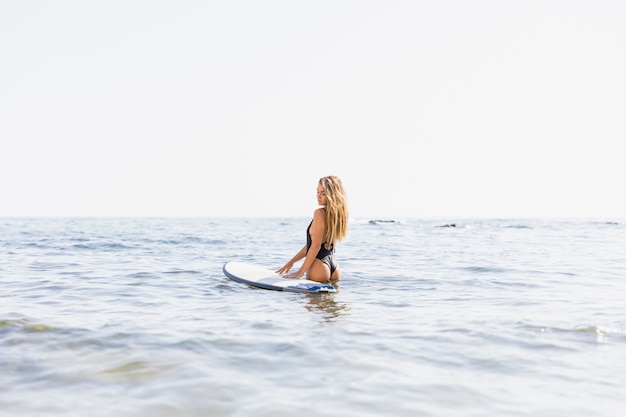 Mujer con tabla de surf en la playa