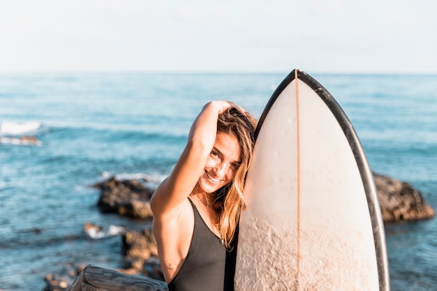 Mujer con tabla de surf en la playa