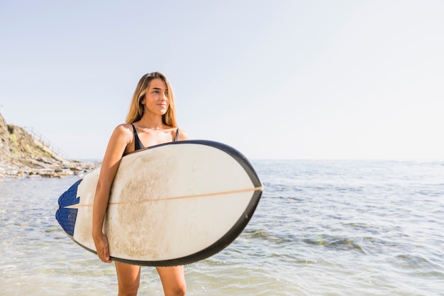 Mujer con tabla de surf en la playa