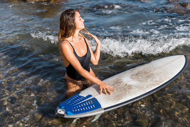 Mujer con tabla de surf en la playa