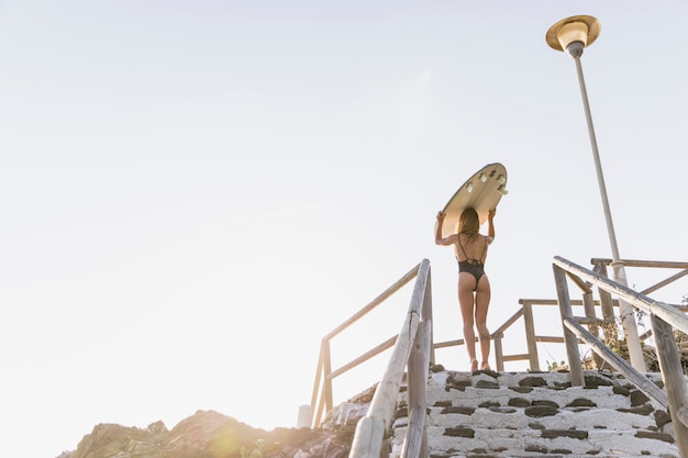 Mujer con tabla de surf en la playa