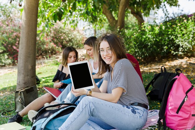 Mujer con tableta con amigos en el parque