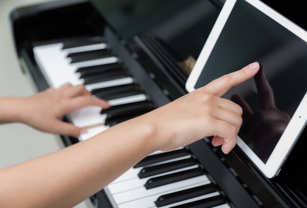 Mujer con tableta aprendiendo a tocar el piano