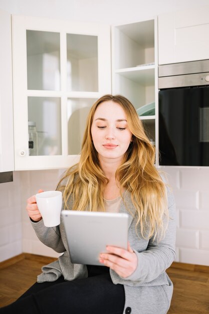 Foto gratuita mujer con tableta y bebida en la cocina