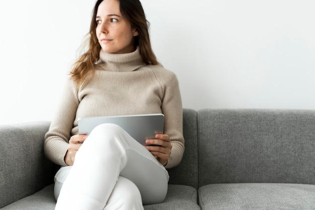 Mujer con tableta digital en un sofá