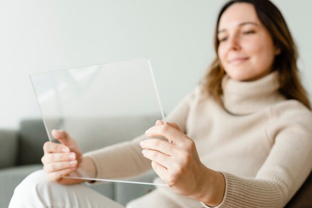 Mujer con tableta transparente en una tecnología innovadora de sofá