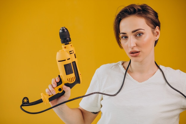 Mujer con taladro eléctrico sobre fondo amarillo