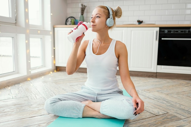 Mujer en tapete con auriculares agua potable