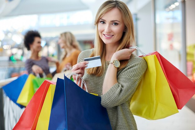 Mujer con tarjeta de crédito y bolsas de compras completas