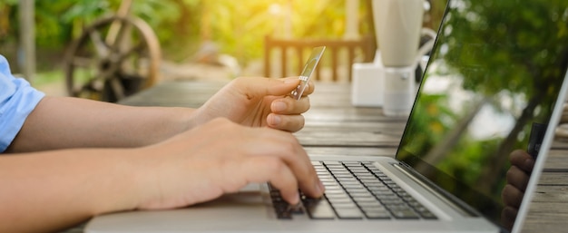 Mujer con tarjeta de crédito en la mano y entrar código de seguridad usando la computadora portátil