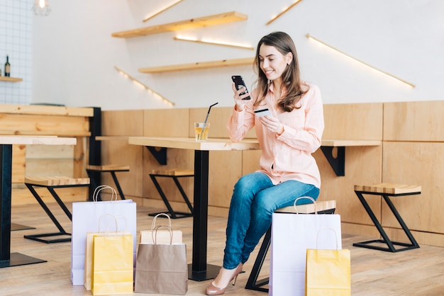 Mujer con tarjeta de crédito usando teléfono inteligente en café