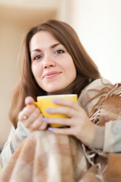 Mujer con taza amarilla en casa