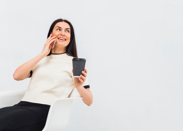 Mujer con taza de café hablando por teléfono