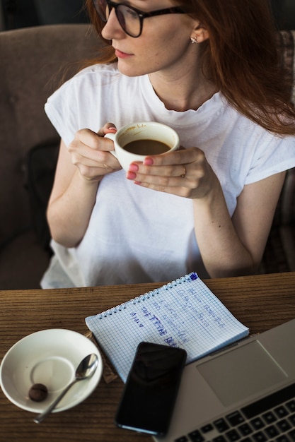 Foto gratuita mujer con taza de café en la mesa