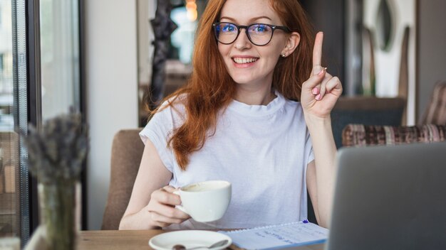 Mujer con taza de café mostrando dedo acusador