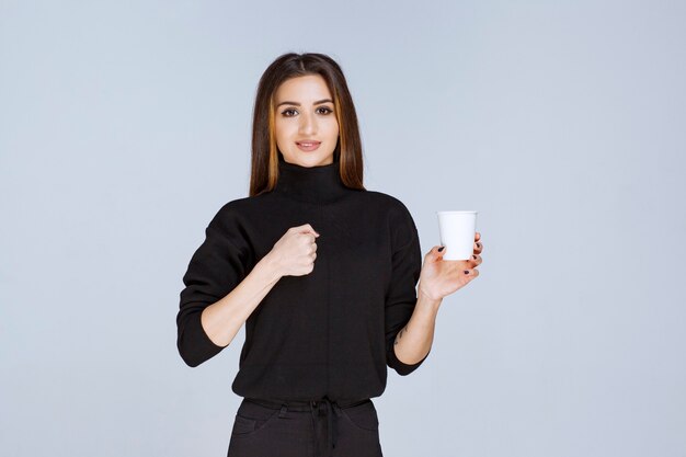 mujer con una taza de café mostrando sus músculos.