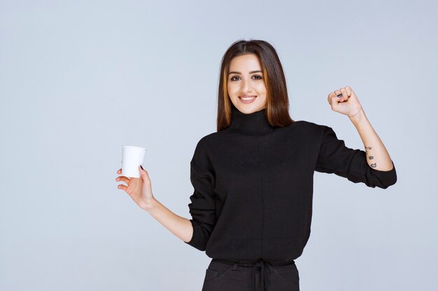 mujer con una taza de café mostrando sus músculos.