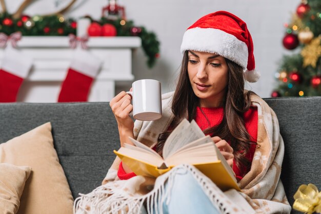 Mujer con taza leyendo interesante libro