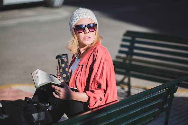 Mujer con taza y libro mirando a otro lado