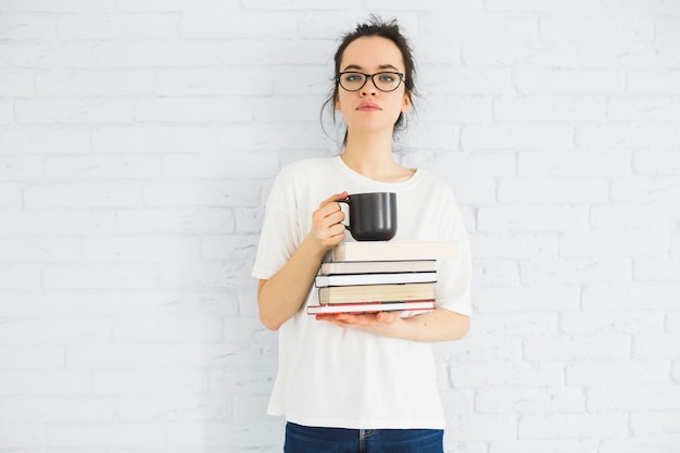 Mujer con taza y libros mirando a cámara