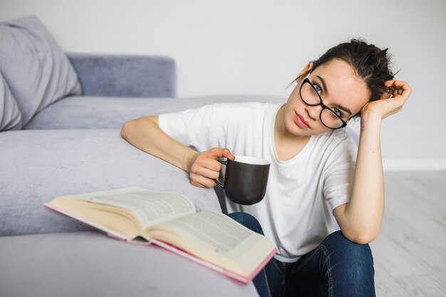 Mujer con taza sentado cerca de libro